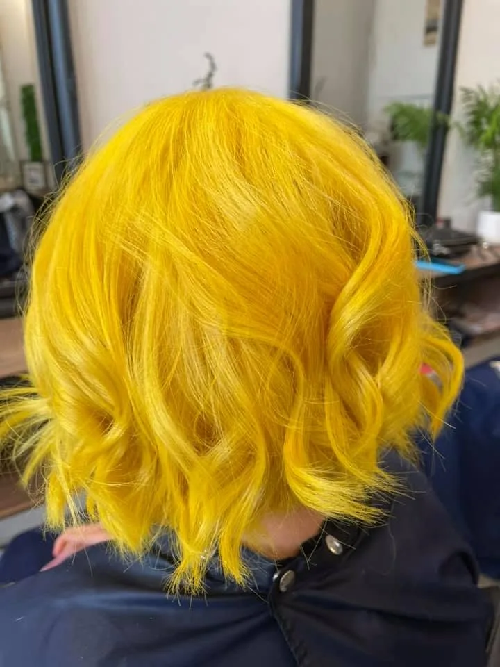 Yellow bob top-down — navy cape, timber bench and potted plant at window