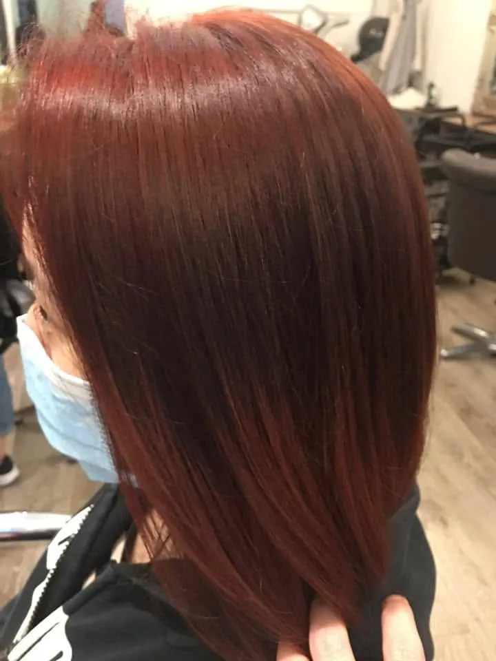 Long straight burgundy-red hair — profile, pale face mask, salon chairs behind