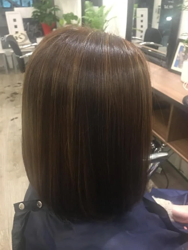 Sleek glossy chestnut bob with caramel highlights — gilt mirrors, navy cape