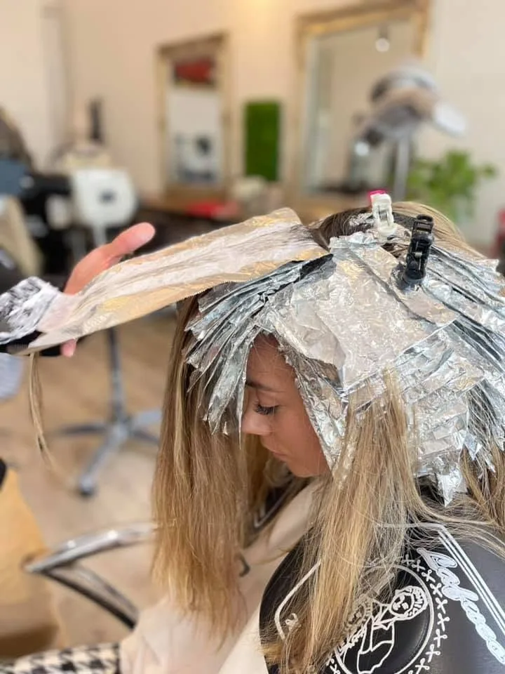 Client mid-foil — silver foils fanned across the crown, two gilt mirrors and timber floor deep behind