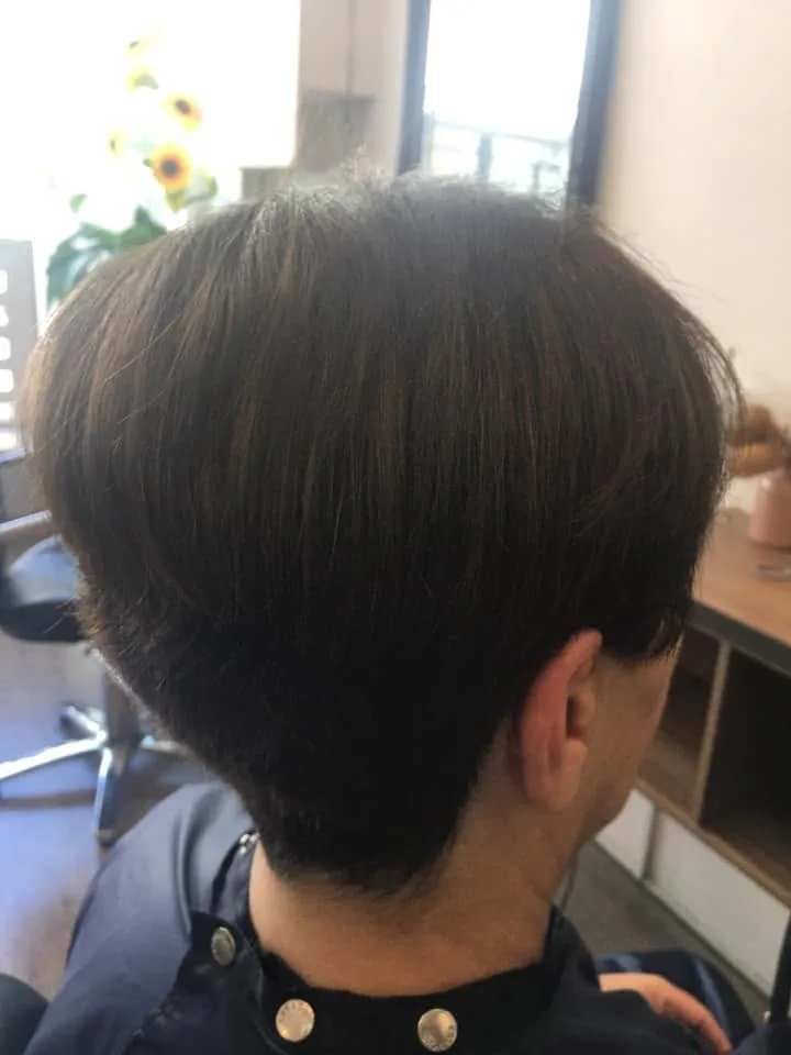 Dark short layered cut with tapered nape — artificial sunflowers and window behind