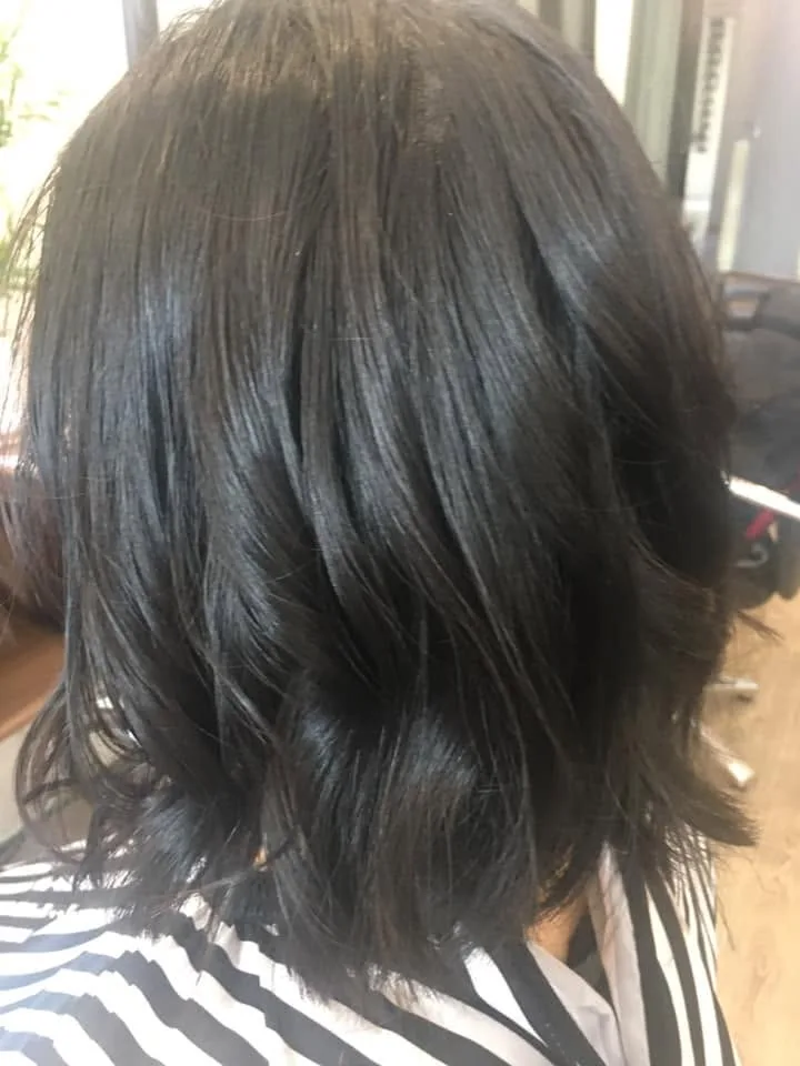 Dark blue-black wavy lob — window light at right, navy cape