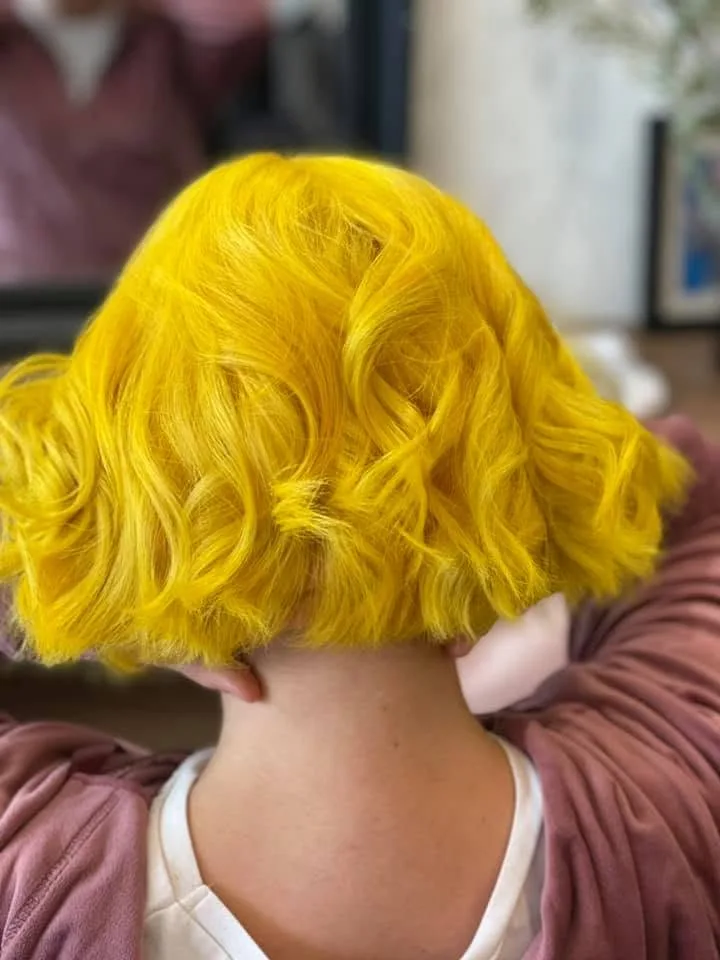 Vivid saturated-yellow wavy bob — back view, dusty-pink hoodie, H.A.T Hair